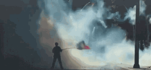 a man is standing in the middle of a smokey area holding a flag .
