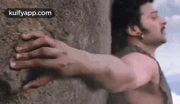 a man 's hand is reaching out towards a rock .