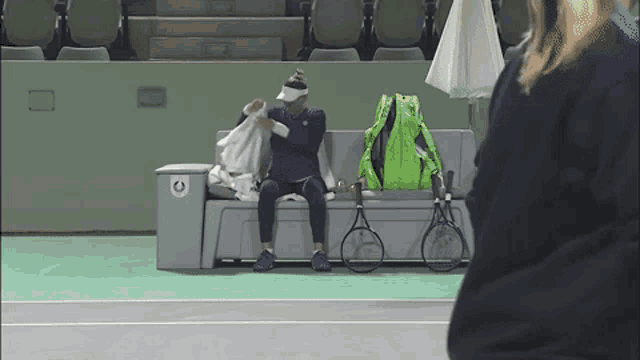 a tennis player sits on a couch with two rackets on the side