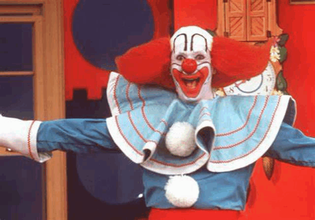 a clown in a blue and white costume is standing with his arms outstretched .