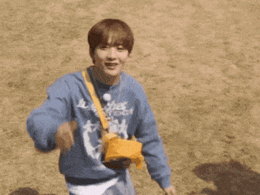 a young man in a blue sweater is holding a yellow bag .