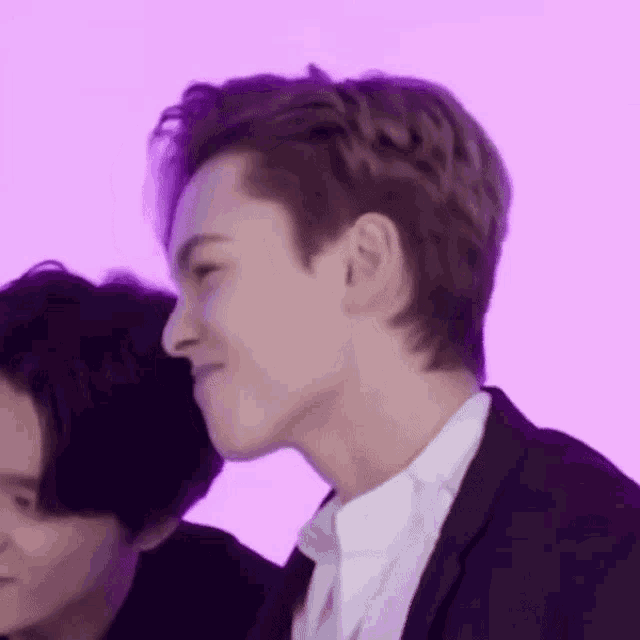 a close up of a person 's face with a purple background and a man in a suit .