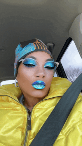 a woman in a yellow jacket has blue lipstick and a monster hat on her head
