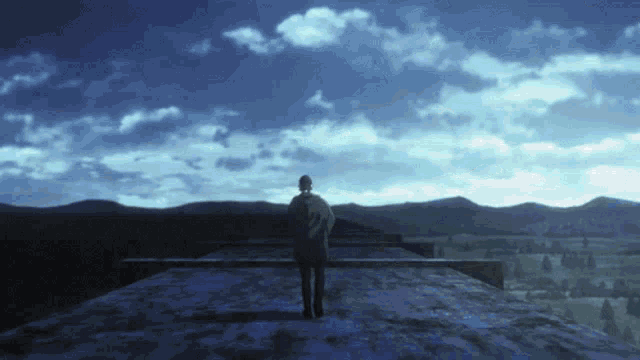 a man standing on top of a building looking at a mountain range