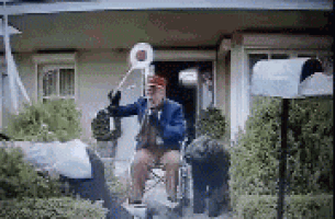 a man in a wheelchair is playing a trumpet in front of a house