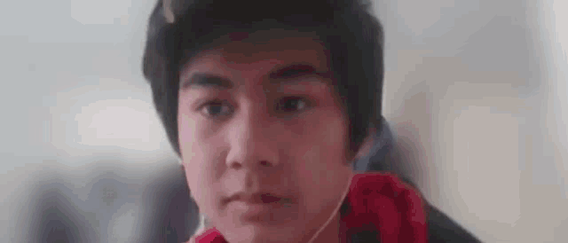 a young man is wearing headphones and looking at the camera .