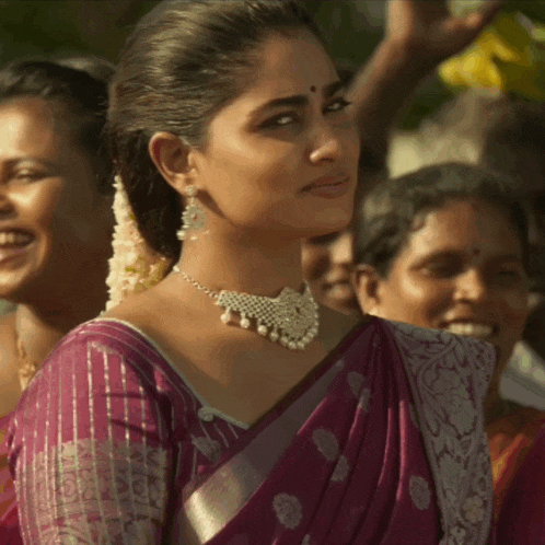 a woman wearing a purple saree and pearl necklace