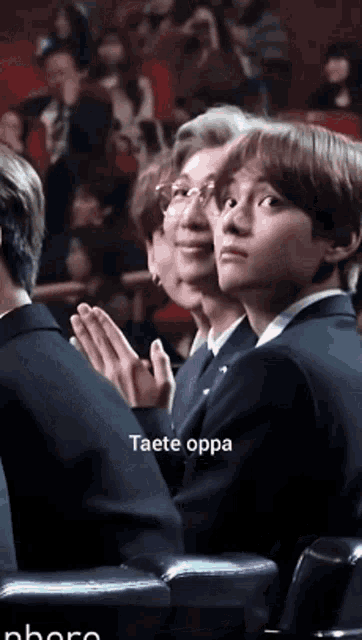 a group of people are sitting in a theatre and one of them is clapping .