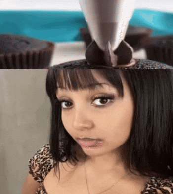 a woman in a leopard print top looks at a chocolate cupcake