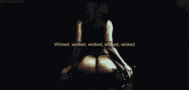 a woman is sitting on a man 's lap in a dark room with a quote on the screen .