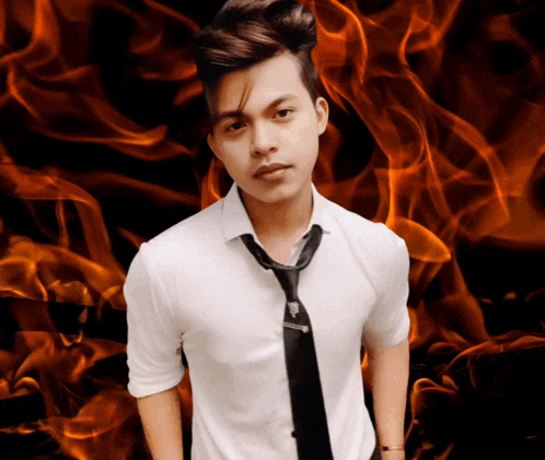 a young man wearing a white shirt and black tie stands in front of a fire background