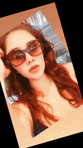 a woman with red hair is wearing sunglasses and taking a picture
