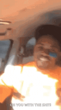 a man is sitting in the passenger seat of a car with a fireball coming out of his mouth .