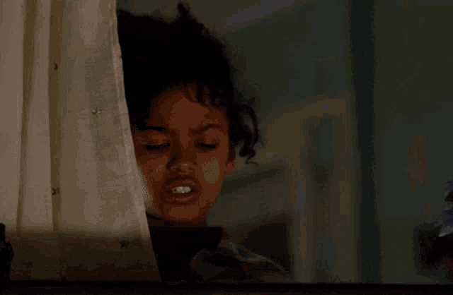 a girl is looking out a window at a blue bird