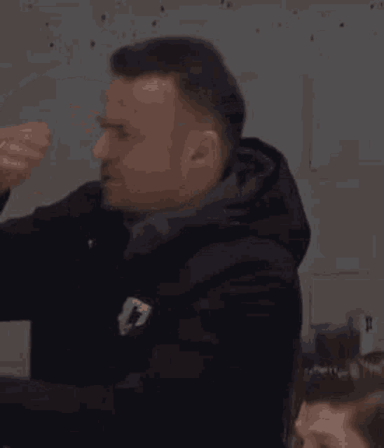 a man is covering his mouth with his hand while laughing .