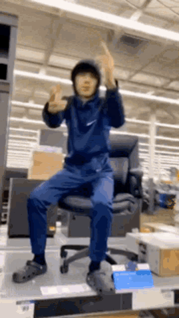 a man in a hoodie is sitting on a chair in a store .