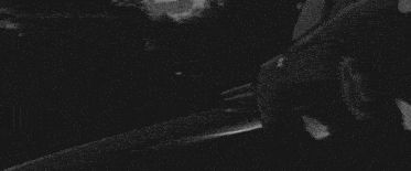 a black and white photo of a car driving down a road at night .