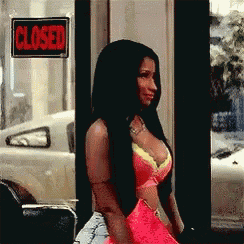 a woman in a pink bra is standing in front of a closed sign .