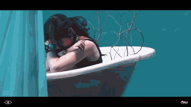 a woman sits in a bathtub with a row logo on the bottom