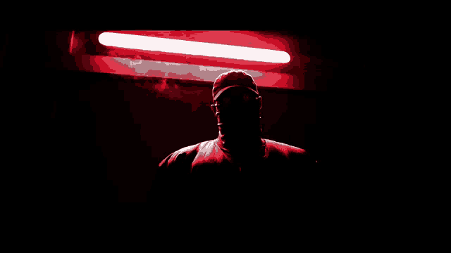 a man in a dark room with a red light shining on him