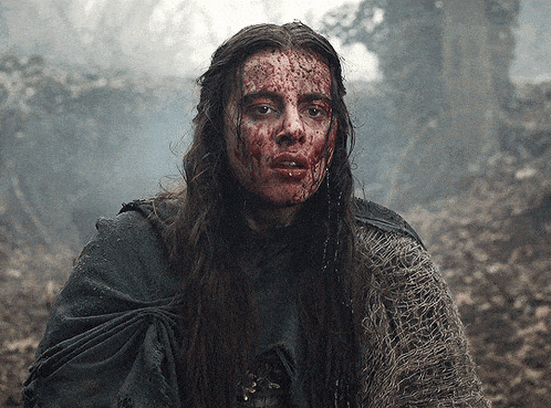a woman with blood on her face is wearing a grey sweater