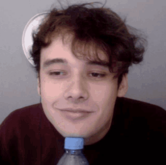 a young man is holding a bottle of water in his mouth
