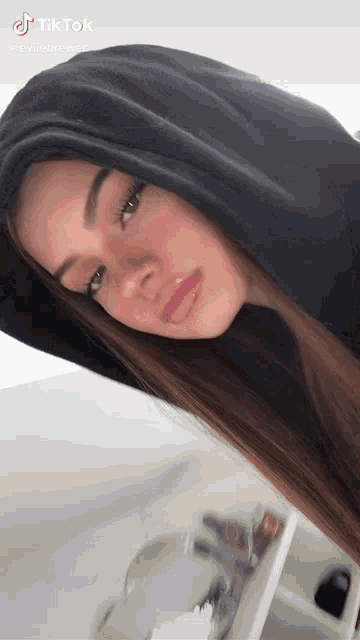 a girl wearing a black hoodie with a tiktok logo on the bottom