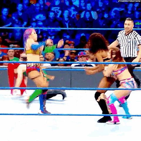 a group of women wrestling in a ring with a referee in the background .