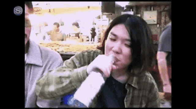 a woman drinking from a bottle with the letter s on the bottom left