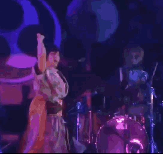 a person is standing in front of a drum set with a purple background .