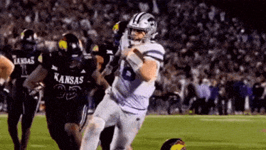 a kansas football player is being tackled by another player on the field .