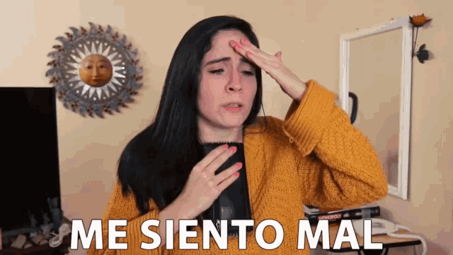 a woman in a yellow sweater holds her hand to her forehead with the words me siento mal behind her