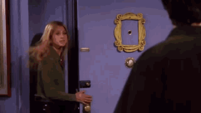 a woman is standing in front of a blue door with a picture frame on it .