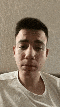 a young man in a white shirt is making a funny face