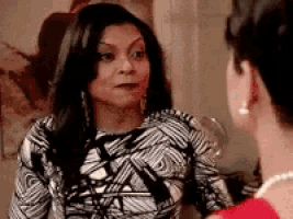 a woman in a black and white dress is talking to another woman in a red shirt .