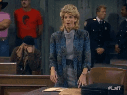 a woman stands in a courtroom with a surprised look on her face ..