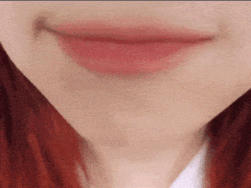 a close up of a woman 's mouth with red hair and pink lipstick .