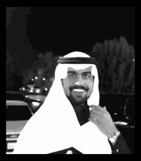 a black and white photo of a man wearing a shawl and a watch