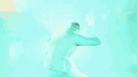 a man in a vest is jumping in the air in a blue light .