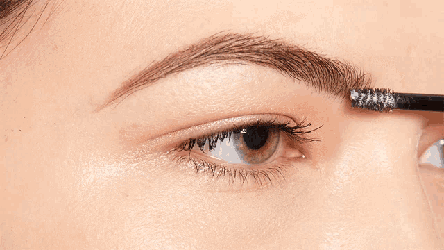 a woman 's eyebrows are being brushed with a brush