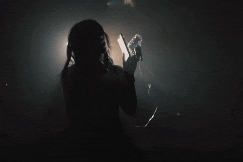 a woman in a dark room giving a peace sign with her hands