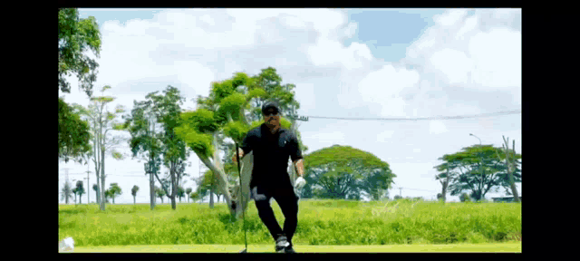 a man standing on a golf course with a golf club in his hand