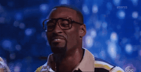 a man with glasses and a beard is smiling on a stage .