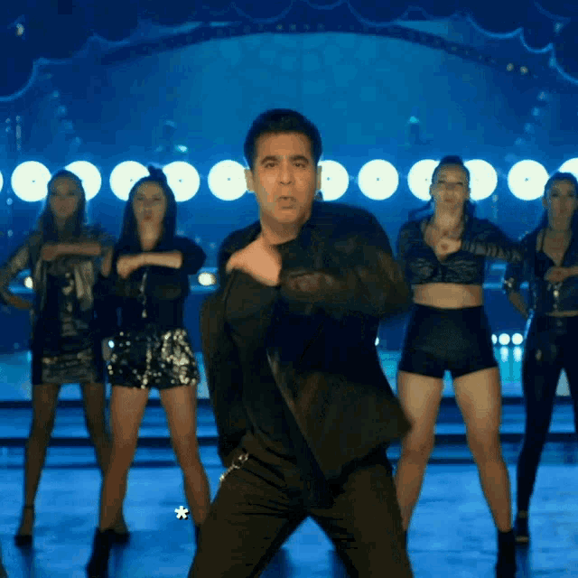 a man in a black jacket is dancing on a stage