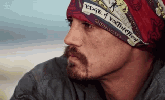 a man wearing a bandana with the words edge of extinction on it
