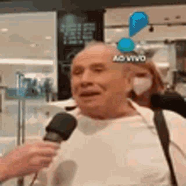 an elderly man is talking into a microphone while wearing a face mask .