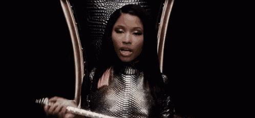 a woman is sitting on a throne holding a microphone and looking at the camera .
