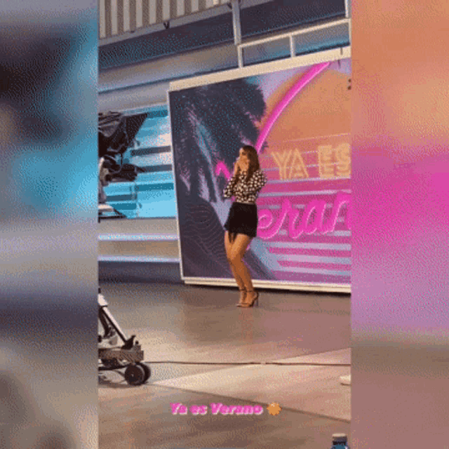 a woman stands in front of a wall that says ya es