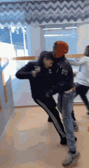 a group of young men are fighting in a room and one of them is wearing a hoodie that says nike