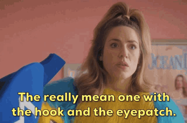 a woman holding a blue shirt with the words " the really mean one with the hook and the eyepatch "